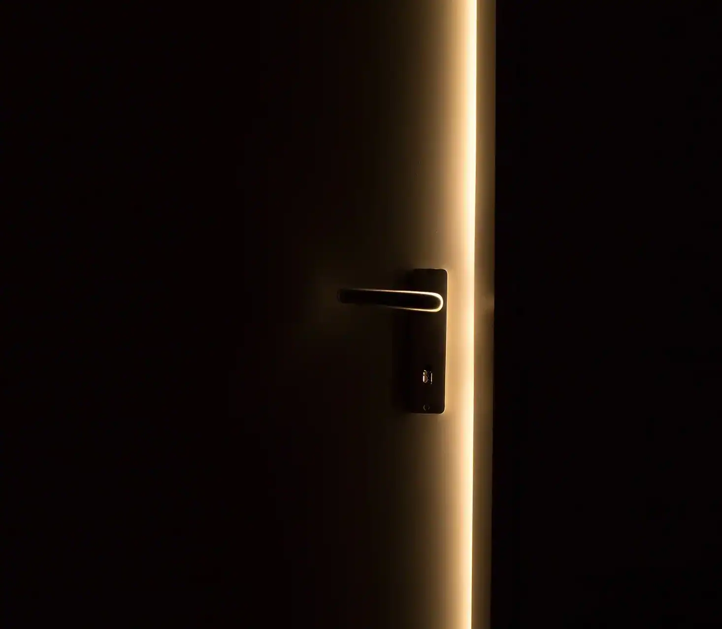 Door Handle Partially Lit By The Light From the Crack in the Opening Door
